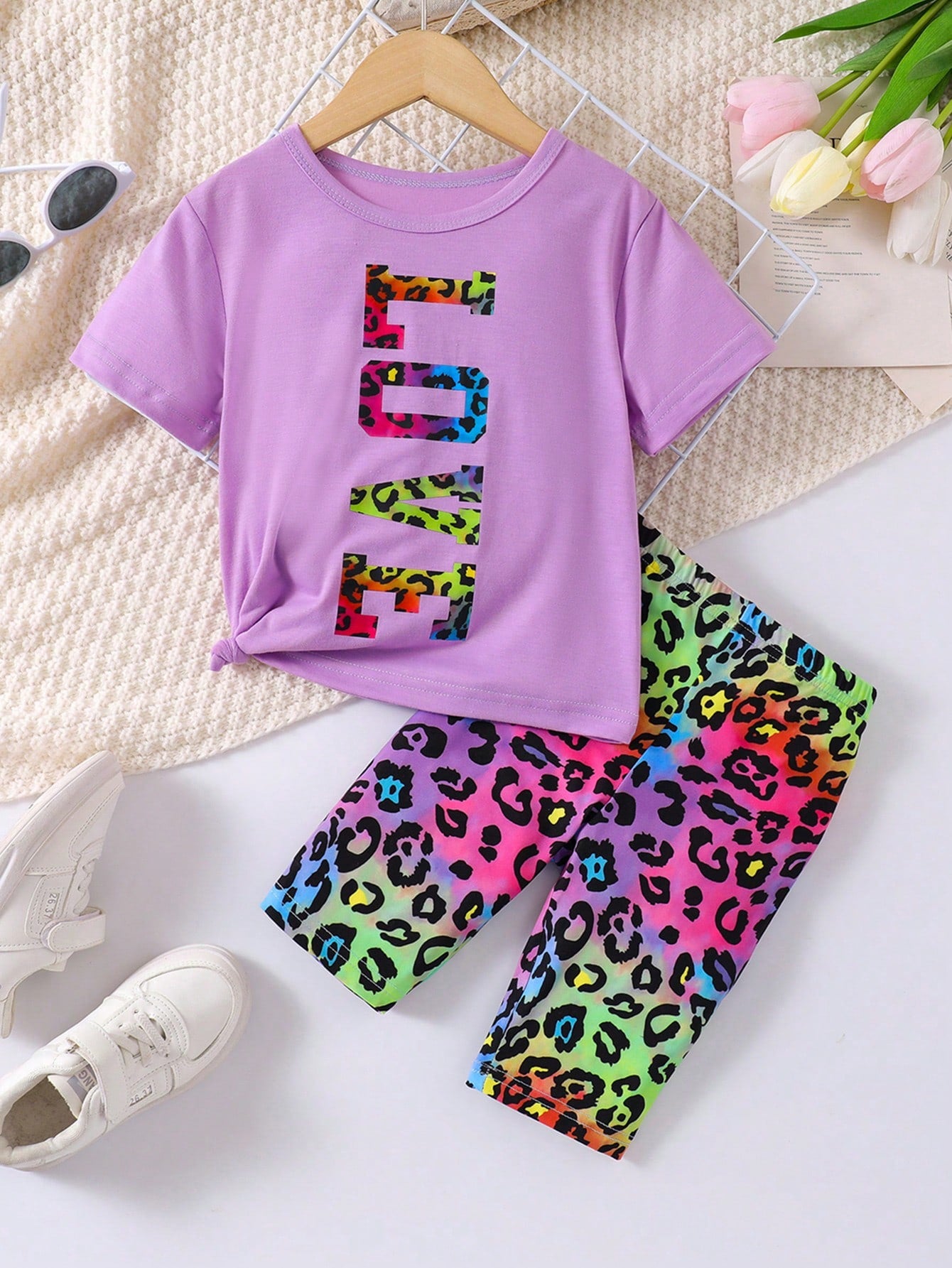 Young Girl Outfit Includes A White Short-Sleeved Round-Neck T-Shirt With Eye-Catching LOVE Letter Print And A Colorful Leopard Print Shorts. It Shows A Stylish And Personalized Style. The Large LOVE Letters On The White T-Shirt Highlight Uniqueness And Co