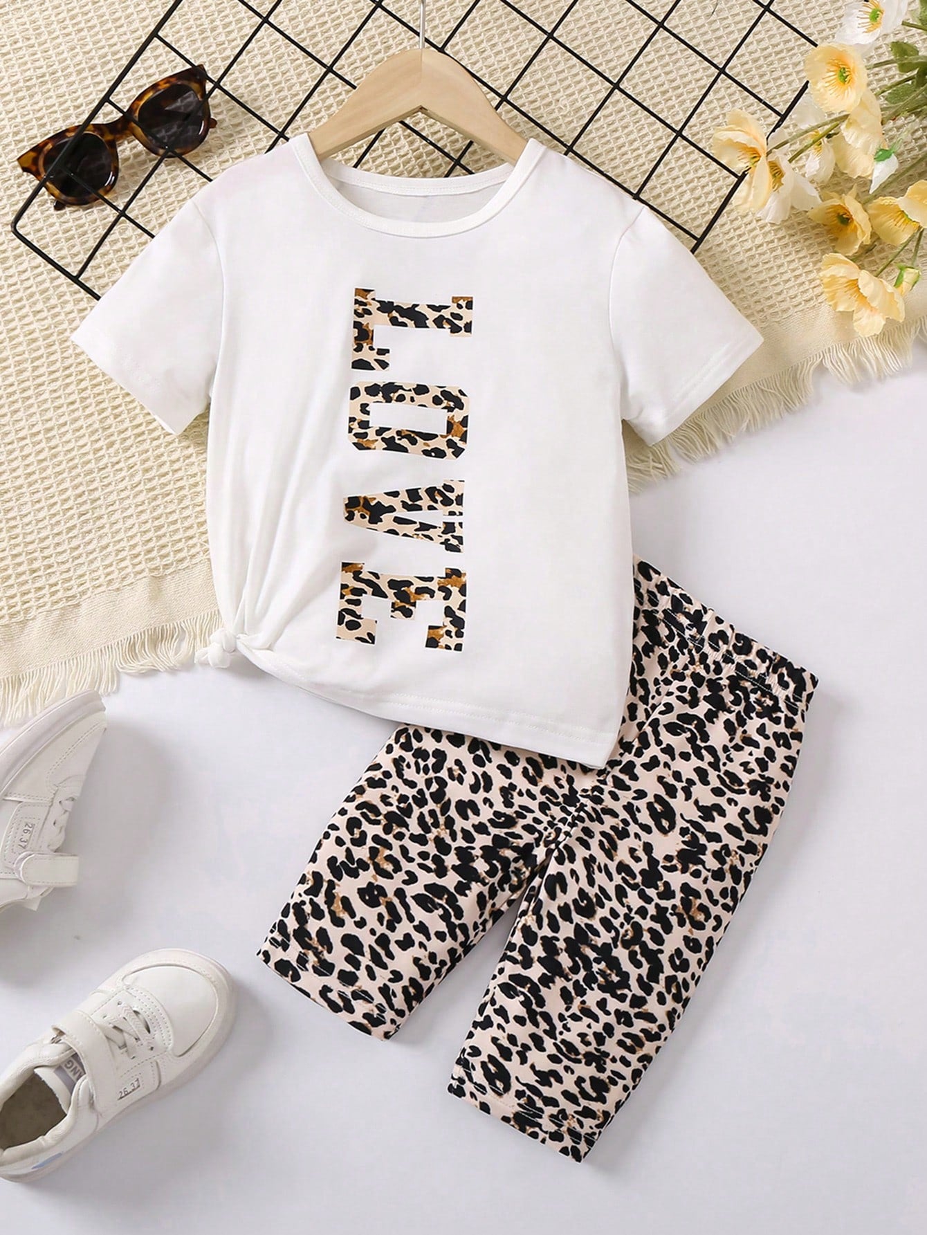 Young Girl Outfit Includes A White Short-Sleeved Round-Neck T-Shirt With Eye-Catching LOVE Letter Print And A Colorful Leopard Print Shorts. It Shows A Stylish And Personalized Style. The Large LOVE Letters On The White T-Shirt Highlight Uniqueness And Co