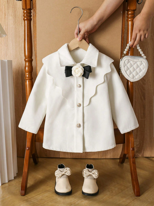 Young Girl Dolly Collar Woolen Coat, In Fresh White Color To Showcase An Elegant And Sweet Vibe. The Coat Features A Adorable Peter Pan Collar Design, Adding A Playful And Vintage Touch. The Collar Is Decorated With A Black Bow Tie, Enhancing The Elegant