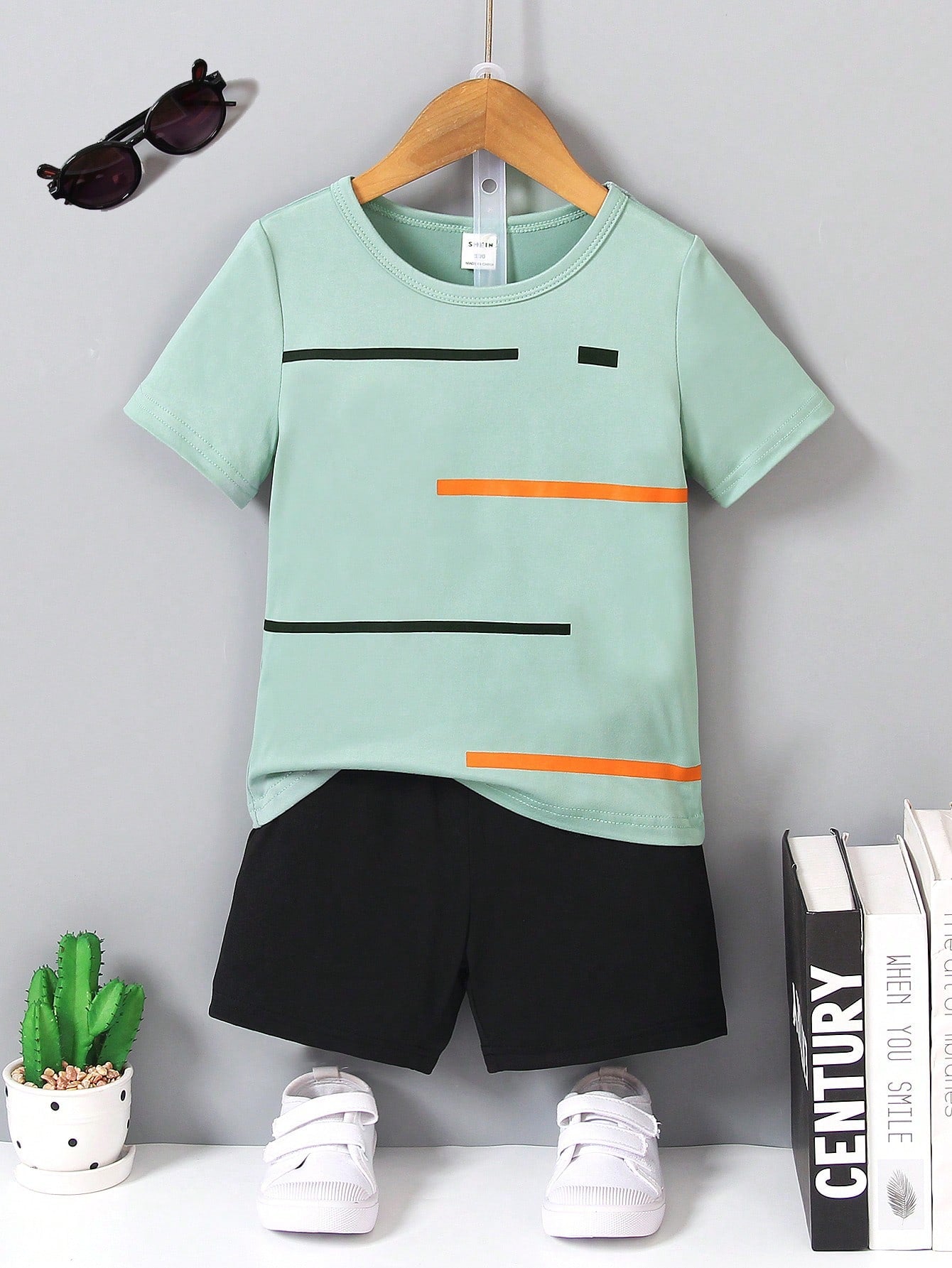 Young Boy Two-Piece Set. Yellow Knitted Striped Printed Round Neck Short Sleeves And Black Casual Knitted Sports Shorts. The Two-Piece Set Is Suitable For Summer.